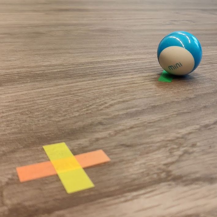 A Sphero Mini robot on a floor marked with coloured tape, used as ground truth for computer vision tracking
